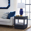 Modern living room with a white sofa, blue and striped pillows, and decorative side tables.