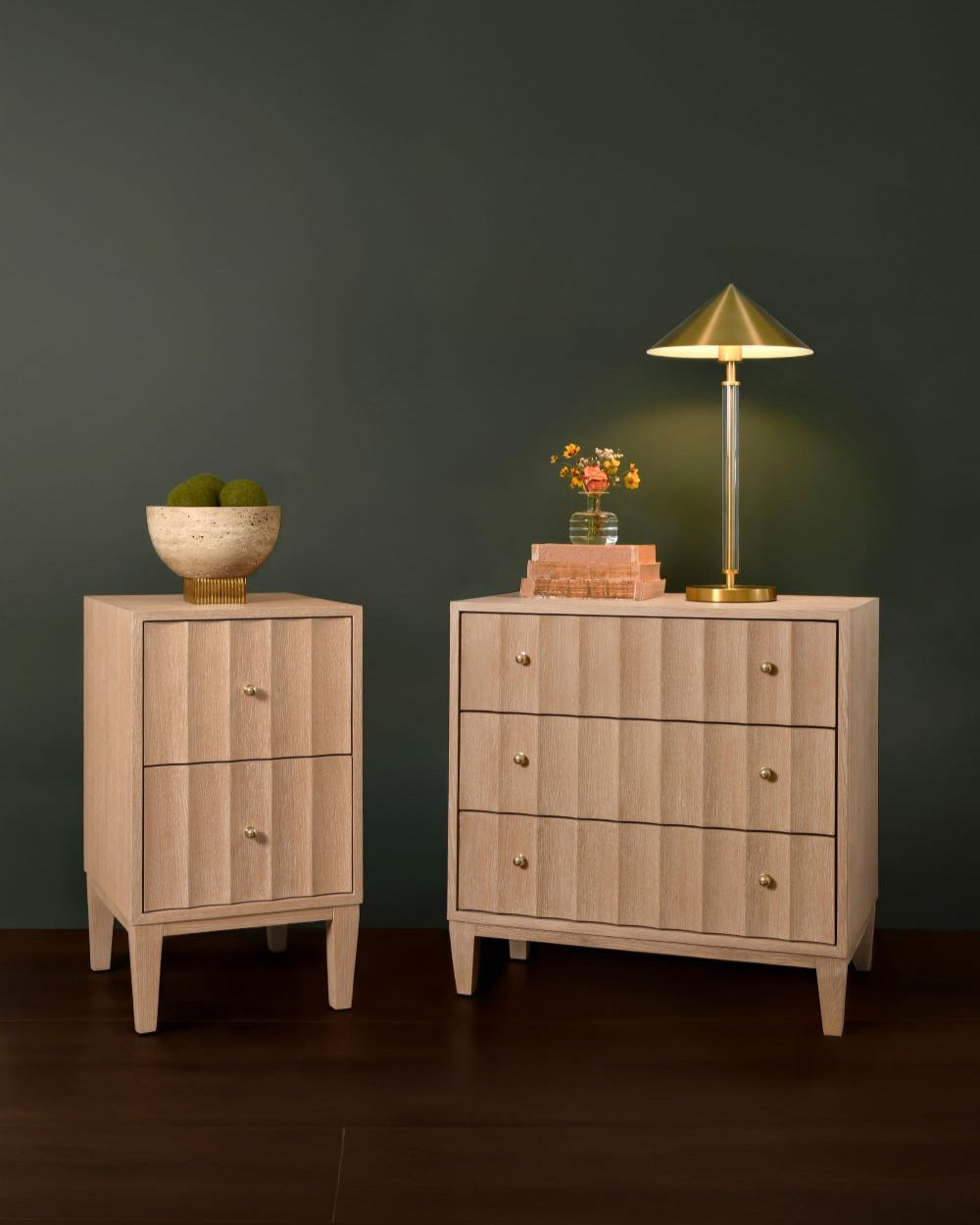 Two wooden nightstands with a lamp and decorative items against a dark wall.
