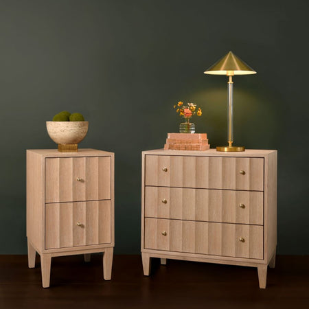 Two wooden nightstands with a lamp and decorative items against a dark wall.