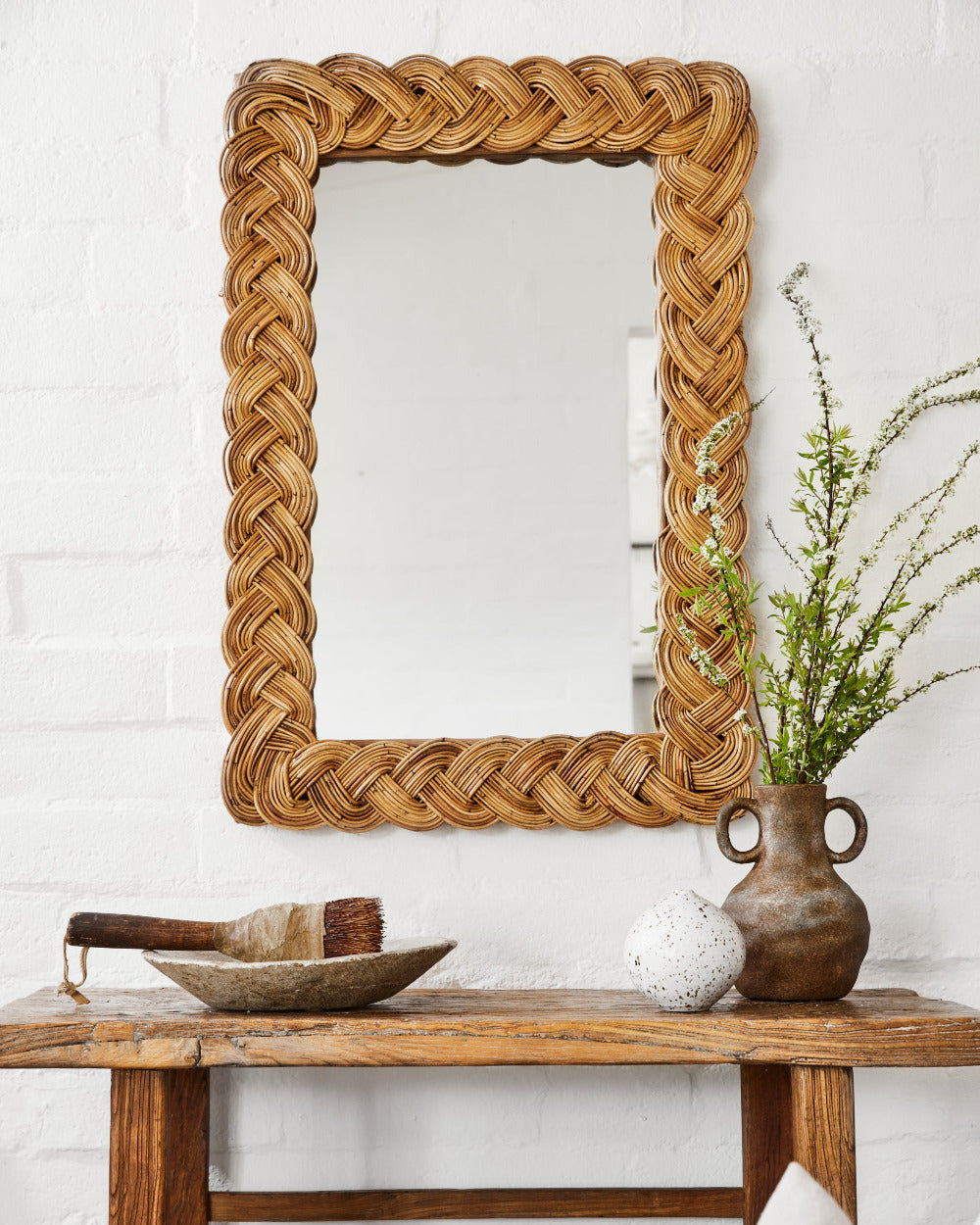 Castello Rectangular Braided Rattan Wall Mirror above rustic bench