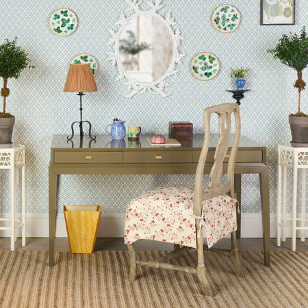 Home office with a desk, chair, and decorative elements on a patterned wall.