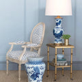 Decorative room setting with a chair, table, Blue Foo Dog Motif Table Lamp against a blue paneled wall.