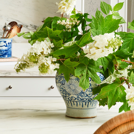 Decorative Sunnflower Temple Jar vase with white flowers and green leaves on a marble surface