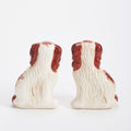 Two ceramic dog figurines with brown and white coloring on a white background