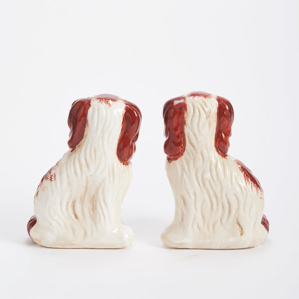 Two ceramic dog figurines with brown and white coloring on a white background
