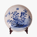 Porcelain chinoiserie style plate with blue floral and bird design on a white background