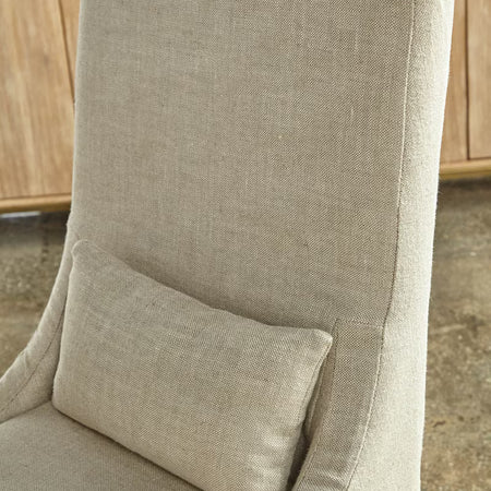 Beige Cora linen chair with a pillow against a wooden cabinet background