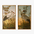 Two framed artworks of cranes in a natural setting with grass and water.