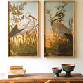 Two framed paintings of birds on a wall above a wooden console table with decorative items.