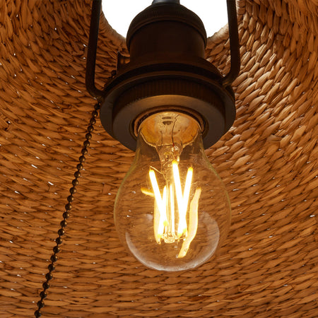 Iron table lamp with seagrass shade illuminated bulb