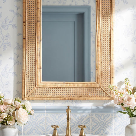 Juno Rattan Mirror styled in blue wallpapered bathroom