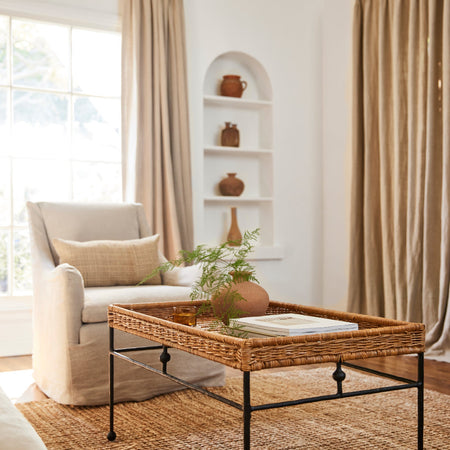 Lacoste Woven Rattan Coffee Table styled in living room with linen chairs