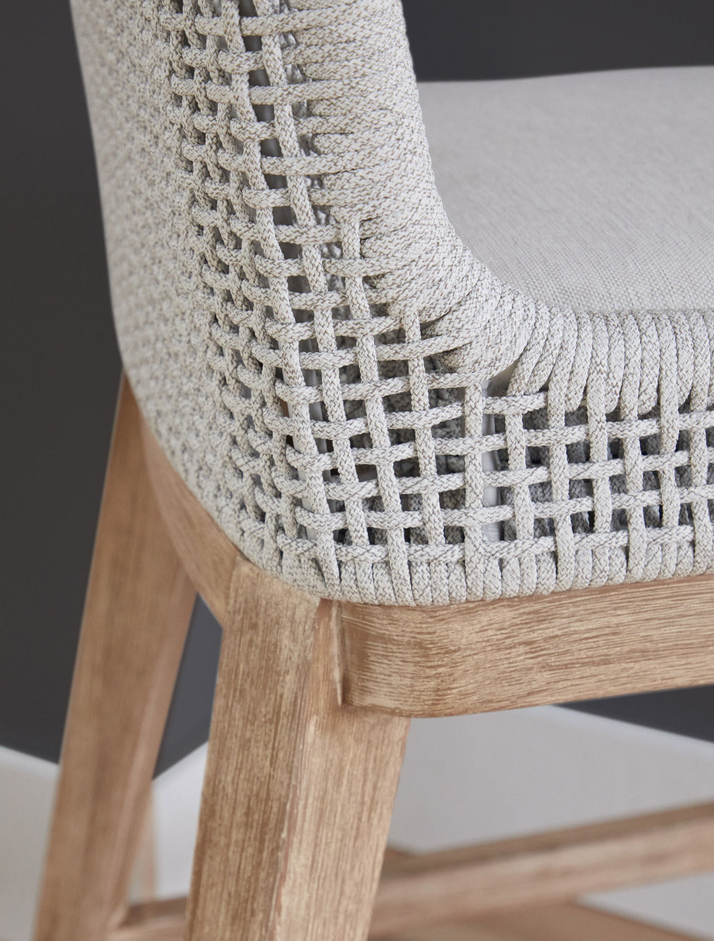 Close-up of a chair with woven backrest and wooden legs on a neutral background