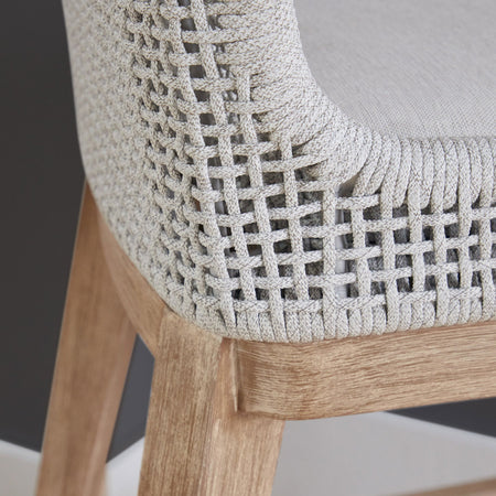 Close-up of a chair with woven backrest and wooden legs on a neutral background