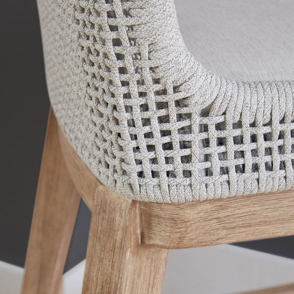 Close-up of a chair with woven backrest and wooden legs on a neutral background