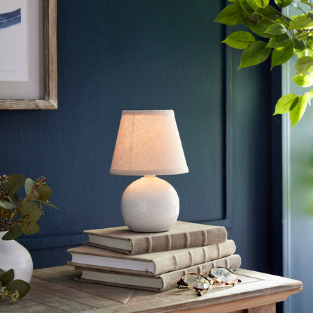 Landry Mini Lamp illuminated on book stack 