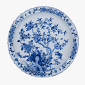 Blue and white ceramic plate with floral and bird design on a white background