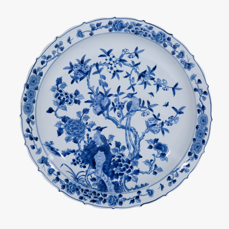 Blue and white ceramic plate with floral and bird design on a white background