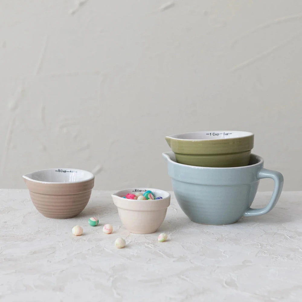 Set of colorful ceramic measuring cups on a light surface with a neutral background