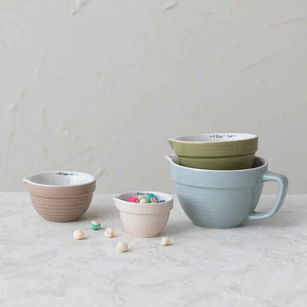 Set of colorful ceramic measuring cups on a light surface with a neutral background