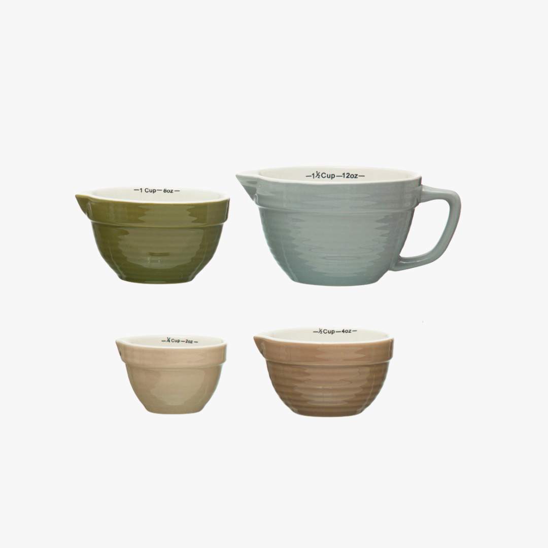 Set of four ceramic measuring cups in different colors on a white background