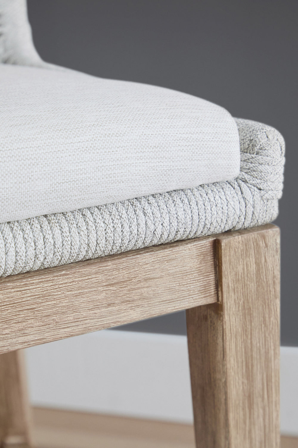 Close-up of a chair with light gray cushioned seat and wooden frame.