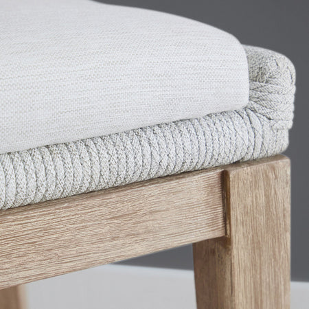 Close-up of a chair with light gray cushioned seat and wooden frame.