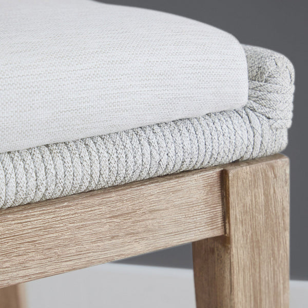 Close-up of a chair with light gray cushioned seat and wooden frame.