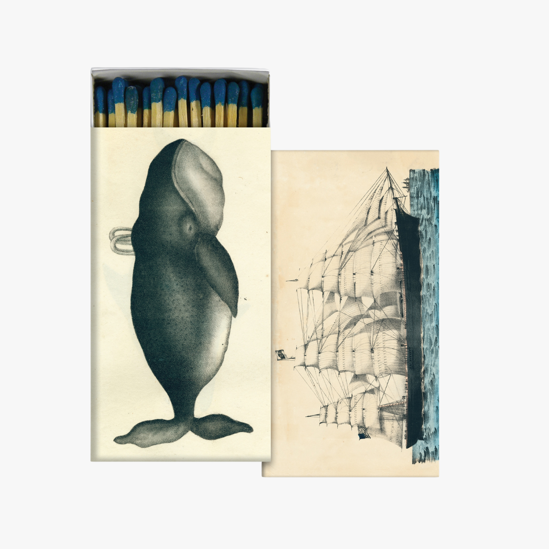 Matchbox with whale illustration on one side and ship illustration on the other, on a white background.